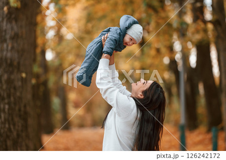 Beautiful mother holding her little son in hands. Standing in the autumn forest 126242172