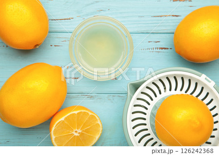 Squeezer and lemons juice on blue wooden background Squeezer and lemons juice on blue wooden background 126242368