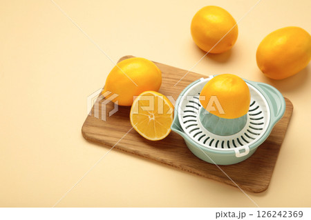 Squeezer and lemons on cutting board on beige background 126242369