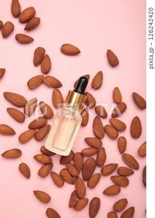 Fresh almond oil with almond nuts on pink background. Vertical photo. Fresh almond oil with almond nuts on pink background. Vertical photo. 126242420
