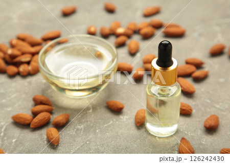 Fresh almond oil with almond nuts on grey background. 126242430