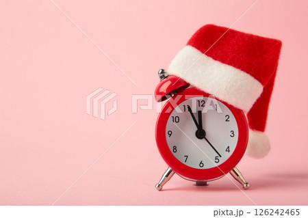 Red alarm clock with Christmas Santa hat on pink background. Top view. 126242465