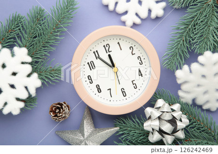 Alarm clock with white snowflakes and fir tree on purple background. 126242469
