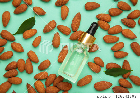 Fresh almond oil with almond nuts on green background. Fresh almond oil with almond nuts on green background. 126242508