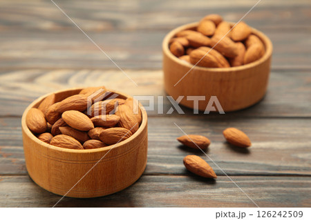 Fresh natural healthy almonds nuts in two wooden bowl on brown wooden background. Fresh natural healthy almonds nuts in two wooden bowl on brown wooden background. 126242509