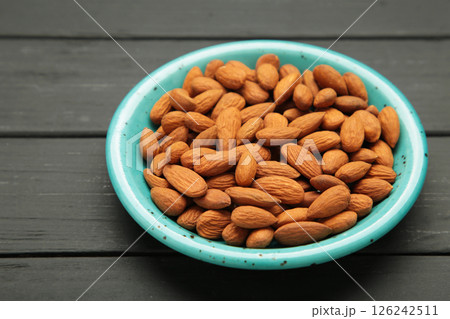 Fresh natural healthy almonds nuts in blue plate on black wooden background. Fresh natural healthy almonds nuts in blue plate on black wooden background. 126242511