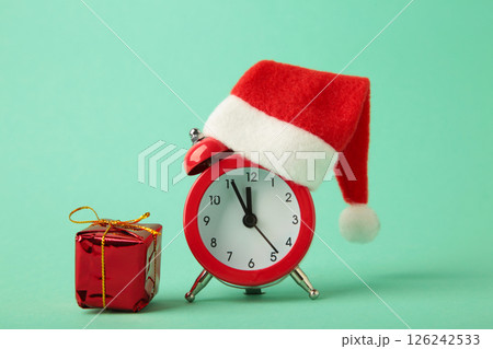 Red alarm clock with Christmas Santa hat on mint background. Top view. 126242533