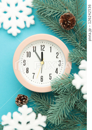 Alarm clock with white snowflakes and fir tree on blue background. Vertical photo 126242536