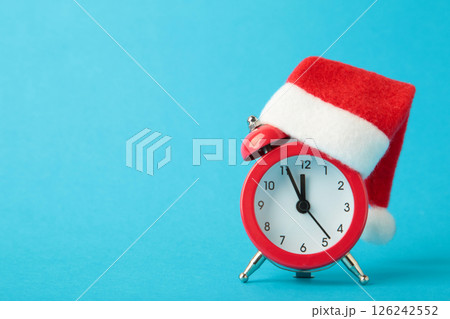 Red alarm clock with Christmas Santa hat on blue background. Top view. 126242552