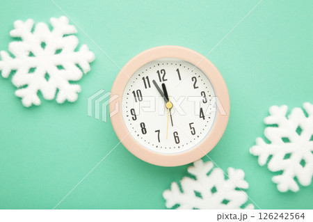 Alarm clock with white snowflakes on mint background. Alarm clock with white snowflakes on mint background. 126242564