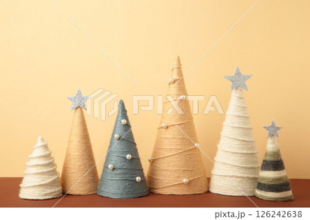Handmade Christmas trees on beige background. Yarn wrapped cone trees. DIY concept Handmade Christmas trees on beige background. Yarn wrapped cone trees. DIY concept 126242638
