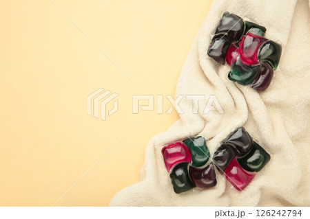 Gel capsules with laundry detergent on beige soft texture Gel capsules with laundry detergent on beige soft texture 126242794