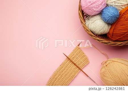 Balls of yarn in basket with knitting needles on pink background. Space for text Balls of yarn in basket with knitting needles on pink background. Space for text 126242861
