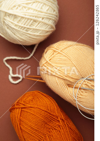 Different yarns, knitting needles on brown background. Autumn. Vertical photo Different yarns, knitting needles on brown background. Autumn. Vertical photo 126242865
