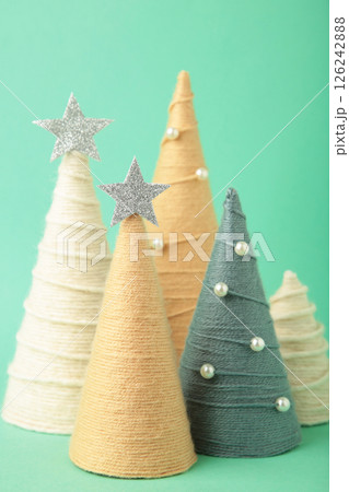 Handmade Christmas trees on mint background. Yarn wrapped cone trees. DIY concept. Vertical photo Handmade Christmas trees on mint background. Yarn wrapped cone trees. DIY concept. Vertical photo 126242888