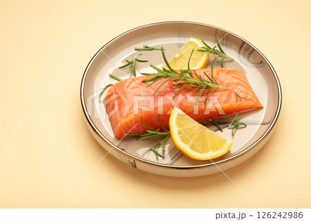 Red fish. Raw salmon fillet with rosemary and lemon on plate on beige background. Red fish. Raw salmon fillet with rosemary and lemon on plate on beige background. 126242986