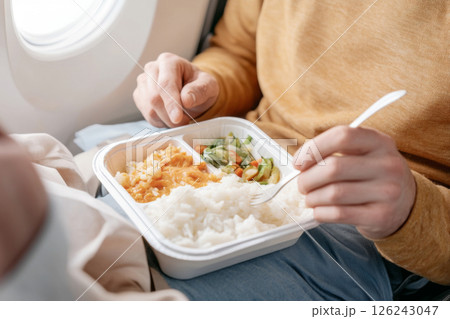 Airplane meal close-up with mans hands holding tray, background 126243047