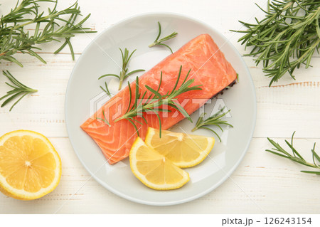 Red fish. Raw salmon fillet with rosemary and lemon on grey plate on white background. Red fish. Raw salmon fillet with rosemary and lemon on grey plate on white background. 126243154
