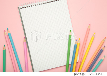 Open notebook with colorful pencil on pink background. 126243518