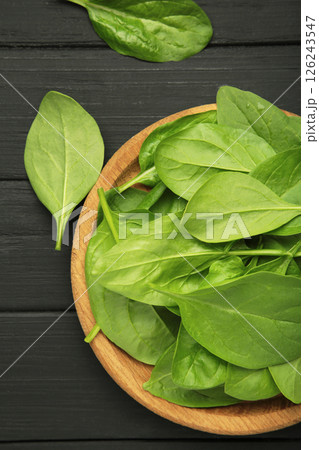 Spinach leaves in a wooden plate on black background. Vertical photo 126243547