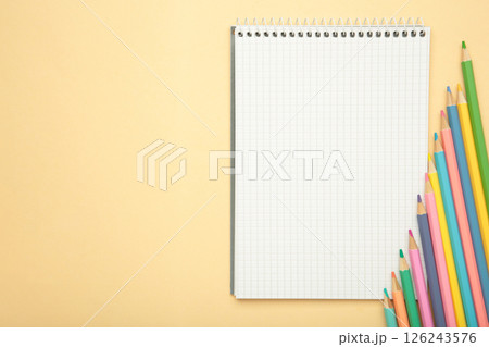 Open notebook with colorful pencil on beige background. 126243576