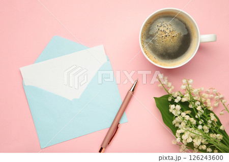 Coffee mug with bouquet of flowers lily of the valley and blue envelope on pink background 126243600