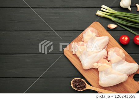 Raw chicken wings with ingredients for cooking on wooden cutting board on black wooden background 126243659