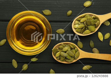 Pumpkin seed oil and seeds in spoon on black wooden background. 126243666