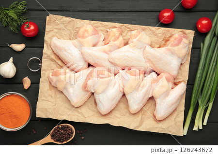 Raw chicken wings with ingredients for cooking on wooden cutting board on black wooden Raw chicken wings with ingredients for cooking on wooden cutting board on black wooden 126243672