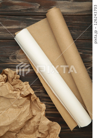 Rolls of white and brown baking paper on brown wooden background. Vertical photo Rolls of white and brown baking paper on brown wooden background. Vertical photo 126243703