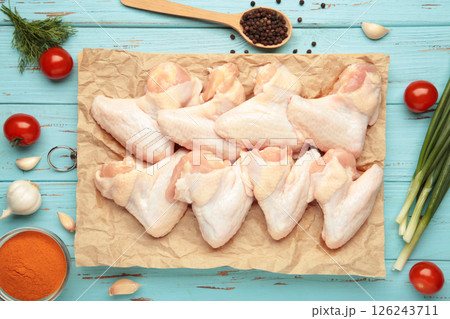 Raw chicken wings with ingredients for cooking on wooden cutting board on blue wooden 126243711