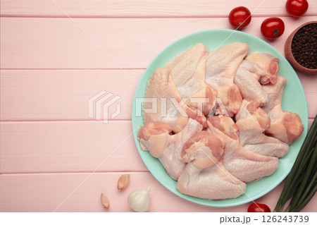 Raw chicken wings with ingredients for cooking on mint plate on pink wooden background Raw chicken wings with ingredients for cooking on mint plate on pink wooden background 126243739