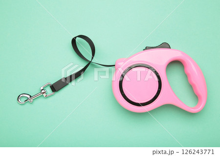 Pink plastic durable and ergonomic leash roulette for pets on mint background. Convenient mechanical device for keeping and controlling dog in street. 126243771