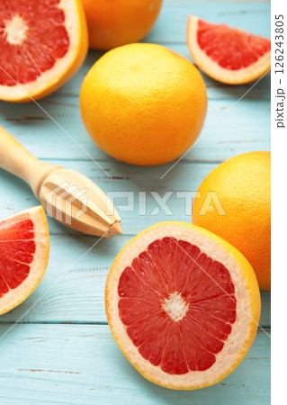 Fresh organic grapefruit and a wooden juicer on blue background, top view. Vertical photo 126243805