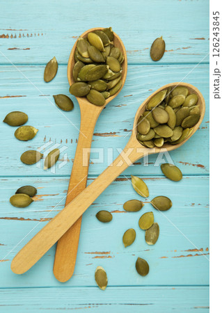 Pumpkin seeds on wooden spoon on blue wooden background. Top view Pumpkin seeds on wooden spoon on blue wooden background. Top view 126243845