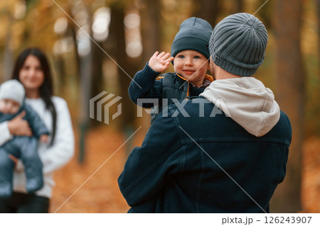 Boy is on the dad's hands. Father with his son on hands walking with mother that is with toddler 126243907