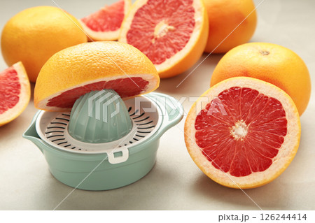 Juicer with freshly squeezed red grapefruit juice,with whole and sliced grapefruit on light background. 126244414