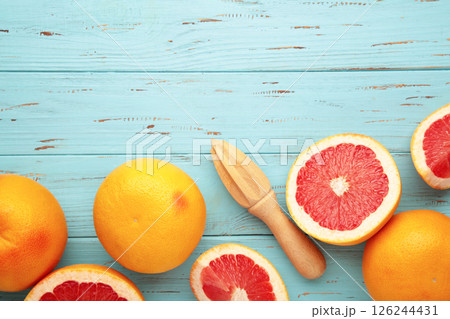 Fresh organic grapefruit and a wooden juicer on blue wooden background, top view. Fresh organic grapefruit and a wooden juicer on blue wooden background, top view. 126244431