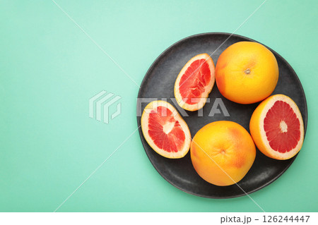 Fresh Organic grapefruit on dark plate on mint background, top view. 126244447