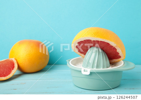 Juicer with freshly squeezed red grapefruit juice,with whole and sliced grapefruit on mint. 126244507
