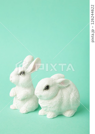 White ceramic rabbits on mint background. Vertical photo White ceramic rabbits on mint background. Vertical photo 126244622