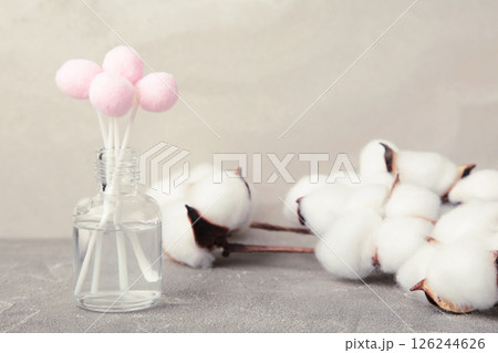 Air freshener on grey. White aroma diffuser bottle with sticks and cotton flower. Minimalism. Top view 126244626