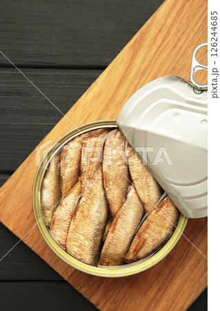 Canned smoked sprat fish in oil in jar on black wooden background. Top view. Canned smoked sprat fish in oil in jar on black wooden background. Top view. 126244685
