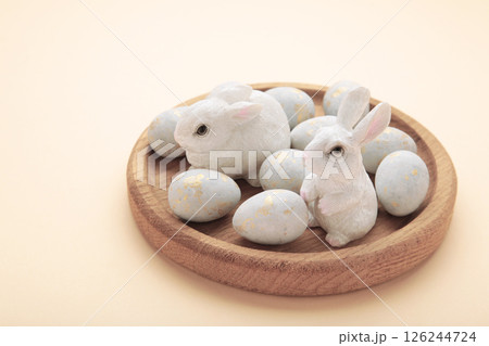 Colorful easter eggs and ceramic bunny figurines on beige background Colorful easter eggs and ceramic bunny figurines on beige background 126244724