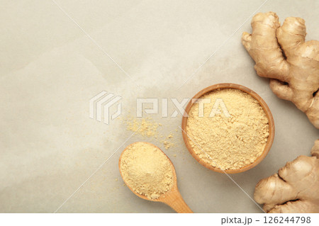 Ginger powder in bowl with fresh ginger root on light background. Top view 126244798