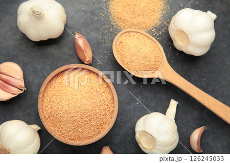 Fresh garlic and garlic powder on dark background. Using spices for meals. Top view 126245033
