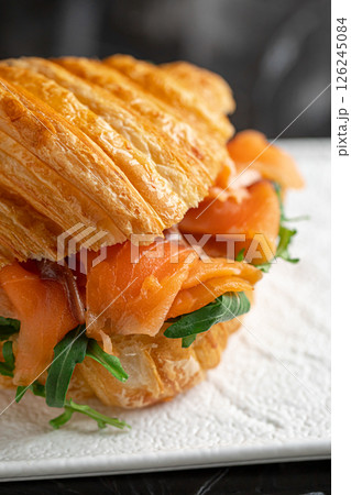 Croissant sandwich with salmon and arugula 126245084