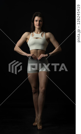 Young beautiful woman with athletic body on dark background. Fitness girl Young beautiful woman with athletic body on dark background. Fitness girl 126245419