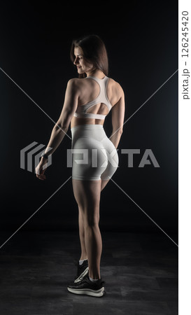 Young beautiful woman with athletic body on dark background. Fitness girl Young beautiful woman with athletic body on dark background. Fitness girl 126245420