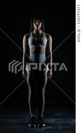 Young beautiful woman with athletic body on dark background. Fitness girl Young beautiful woman with athletic body on dark background. Fitness girl 126245421